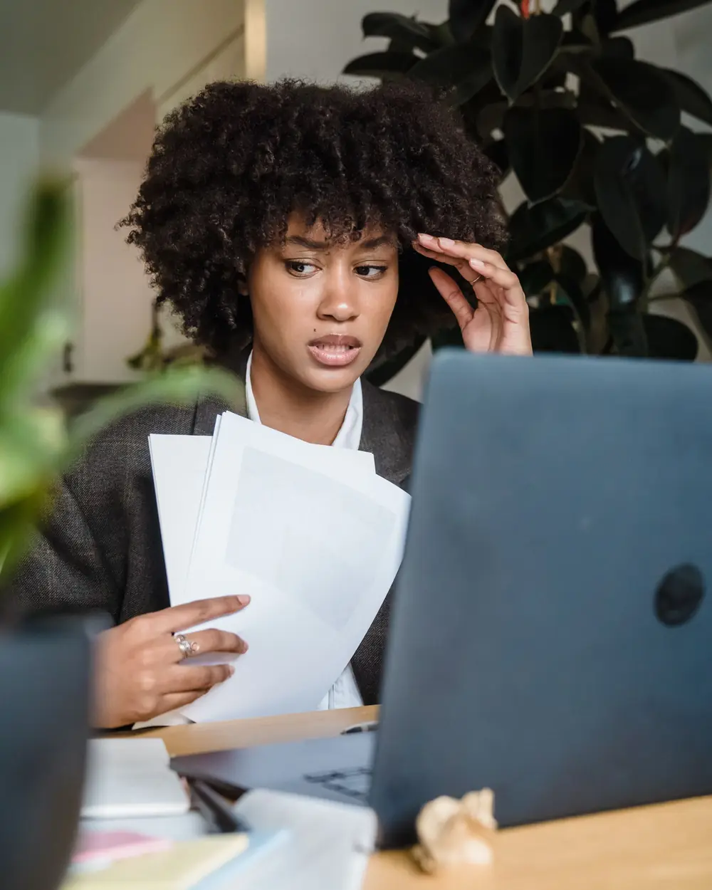A small business owner at her desk checking invoices on a laptop